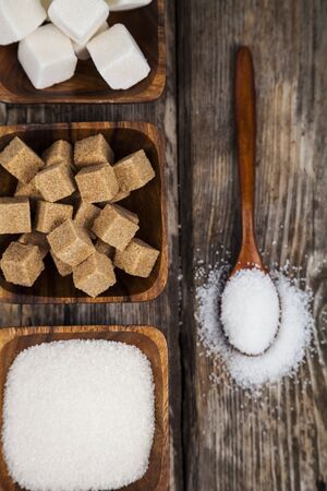 Sugar in a wooden bowls and a spoon on an old wooden background, top view.の写真素材