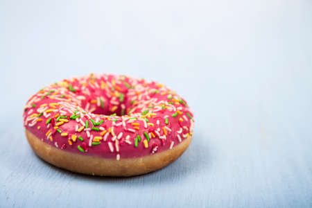 Pink donut close-up on a wooden background. Delicious dessert.の写真素材