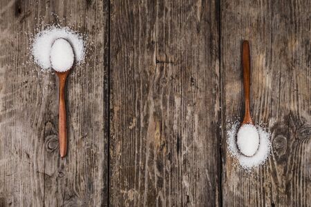 Two wooden spoons with sugar on an old wooden background, top view. Place for text.の写真素材