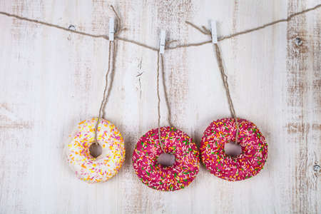 Three donuts on a rope on a wooden background. Delicious and sweet dessert.の写真素材