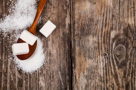 Wooden spoon with sugar on an old wooden background, top view.の写真素材