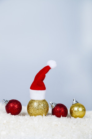 Red Christmas ball in a Santa cap and balls in the snow. Decor for the New Year or Christmas.の写真素材