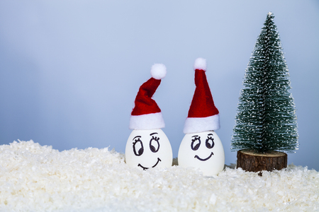 Two eggs in Christmas caps  and a Christmas tree on snow. Card for the New Year and Christmasの写真素材