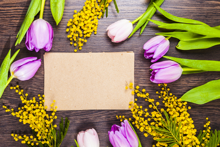 Bouquet of tulips, mimosa and paper on a wooden background. Still life with beautiful flowers on holiday.の写真素材