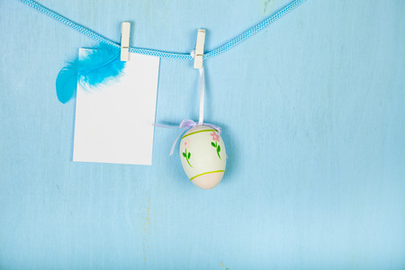 Easter Eggs,feathers and paper on a rope on a blue wooden background.  Easter still life can be used as a postcard.の写真素材