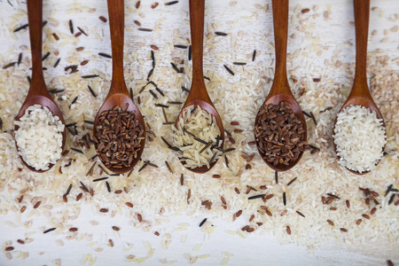  Five spoons with different grades of rice on an old wooden background. Ingredient for a healthy diet.の写真素材