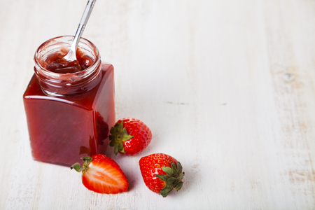 Jar of strawberry jam and ripe strawberries on a wooden background. Delicious dessert.の写真素材