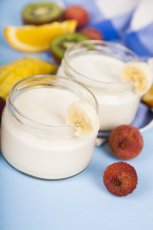 Yogurt with tropical fruits on a wooden background. Tasty breakfast. Healthy eating.の写真素材