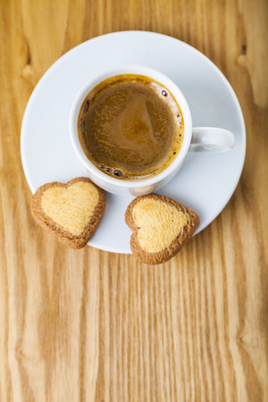 Heart-shaped biscuits and coffee on a wooden background. Romantic breakfast. Greeting card for St. Valentine's Day.の写真素材