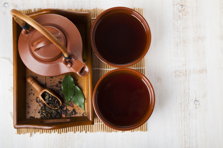 Ceramic teapot and tea leaves  on a wooden tray, top view. Oriental tea.の写真素材