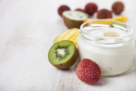 Yogurt with tropical fruits on a wooden background. Tasty breakfast. Healthy eating.の写真素材