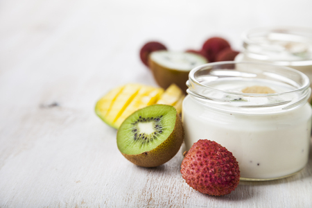 Yogurt with tropical fruits on a wooden background. Tasty breakfast. Healthy eating.の写真素材