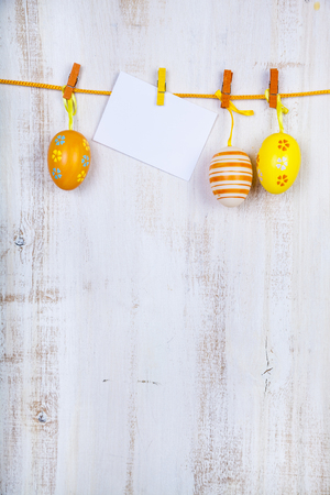 Easter Eggs and paper on a rope on a  wooden background.  Easter still life can be used as a postcard.の写真素材