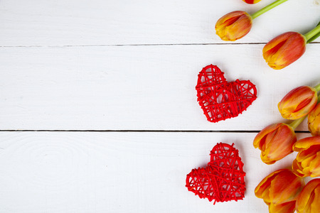 Bouquet of tulips and red hearts on a white wooden background. Greeting card for Valentine's Day,...