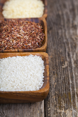 Three bowls with different varieties of rice on a wooden background. Ingredient for a healthy diet.の写真素材