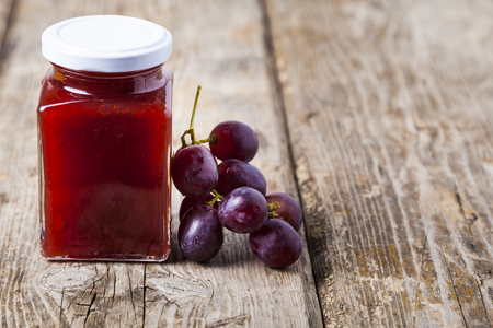 Jar of  jam and grapes on a wooden background. Delicious dessert.の写真素材