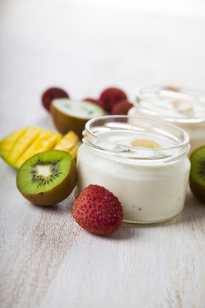 Yogurt with tropical fruits on a wooden background. Tasty breakfast. Healthy eating.の写真素材