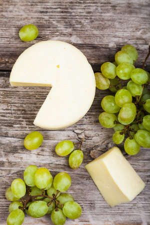 Cheese and grapes on an old wooden table. Delicious appetizer.の写真素材
