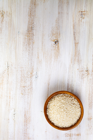 Raw  steamed rice in a bowl on a wooden background. Ingredient for a healthy diet.の写真素材