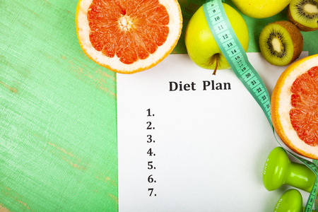 Food and sheet of paper with a diet plan on a wooden background. Concept of diet and healthy lifestyle.の写真素材