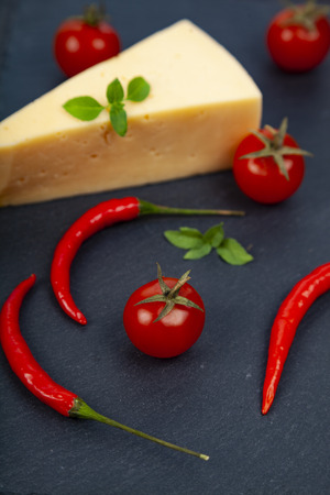 Cheese, cherry tomatoes,chilli and basil  on a dark background.の写真素材