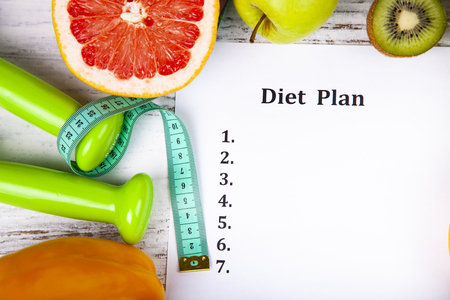 Food and sheet of paper with a diet plan on a wooden background. Concept of diet and healthy lifestyle.の写真素材