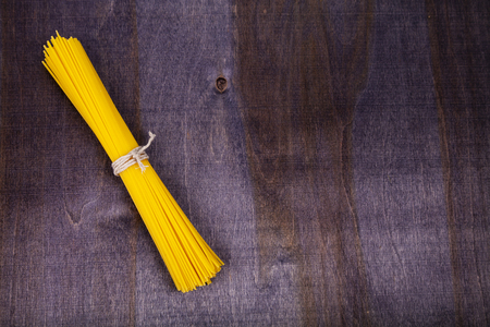 Spaghetti on a dark wooden background. Raw pasta close-up.の写真素材