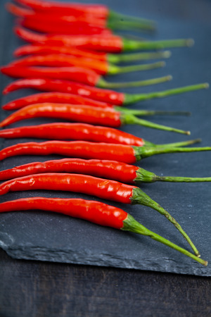 Red chilli pepper is a dark background. Chili pepper is decomposed in a row.の写真素材