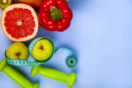 Food for  diet and dumbbells on a wooden background. Concept of diet and healthy lifestyle.の写真素材
