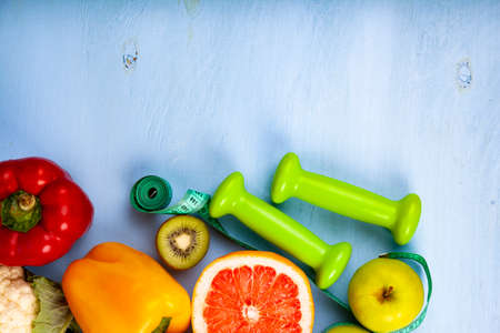 Food for  diet and dumbbells on a wooden background. Concept of diet and healthy lifestyle.の写真素材