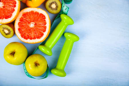 Food for  diet and dumbbells on a wooden background. Concept of diet and healthy lifestyle.の写真素材