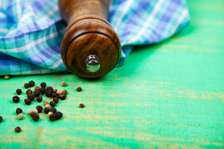 Pepper mill and bell pepper on a green wooden table