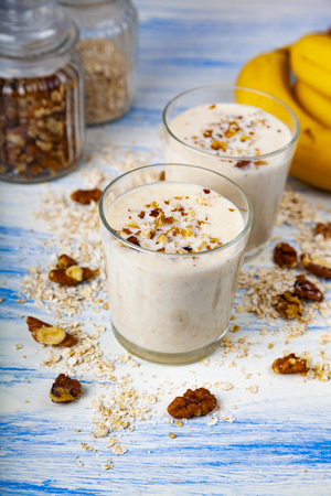 Smoothies with a banana, walnut and oat flakes on a blue wooden table. Delicious dessert.の写真素材