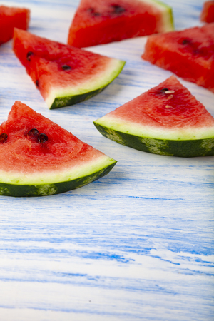 Pieces of watermelon on a blue wooden table. Delicious dessert.の写真素材