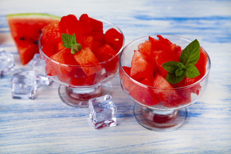 Pieces of watermelon and mint in a plate on a wooden table. Delicious dessert.の写真素材