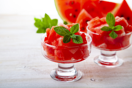 Pieces of watermelon and mint in a plate on a wooden table. Delicious dessert.の写真素材