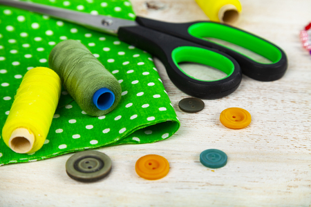 Sewing accessories and green fabric on a  wooden background. Fabrics, measuring tape, pins, buttons and thread.の写真素材