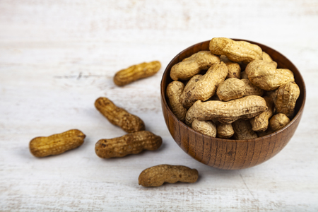 Peanuts in a wooden bowl on the table. Delicious and healthy nuts.の写真素材