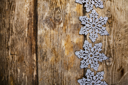 Silvery snowflakes on an old brown wooden background. Christmas decor.の写真素材