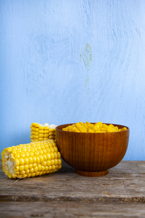 Ripe corn in a bowl on a wooden table.の写真素材