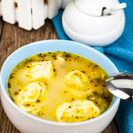 Chicken soup with dumplings on a wooden tableの写真素材