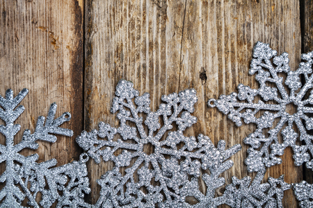Silvery snowflakes on an old brown wooden background. Christmas decor.の写真素材