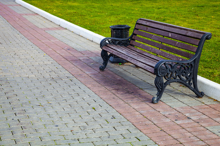 Bench, a stone walkway in the park  and green lawn. Beautiful summer city park for walking.
