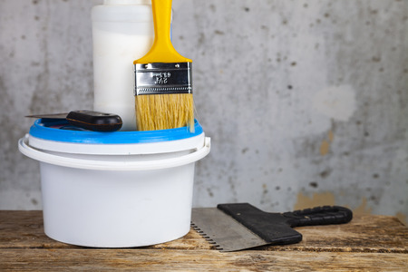 Items for home or office renovation against a gray wall. Paint can and brush on the table.の写真素材