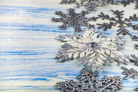 Christmas snowflakes on blue wooden background. Border of silver snowflakes.の写真素材