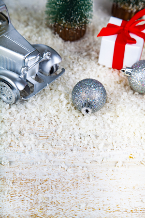 Silver retro car, Christmas trees and a Christmas present on the snowの写真素材