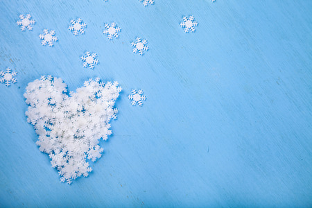 Christmas snowflakes on blue wooden background. Heart of white snowflakes.の写真素材