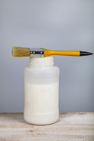 Paint can and brush on the table. Items for home or office renovation on gray background.の写真素材