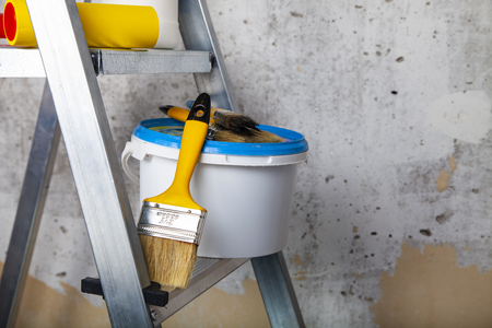 Paint,roller and brushes on the stepladder. Items for home or office renovation against a gray wall.の写真素材