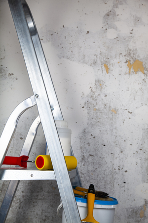 Paint,roller and brushes on the stepladder. Items for home or office renovation against a gray wall.の写真素材